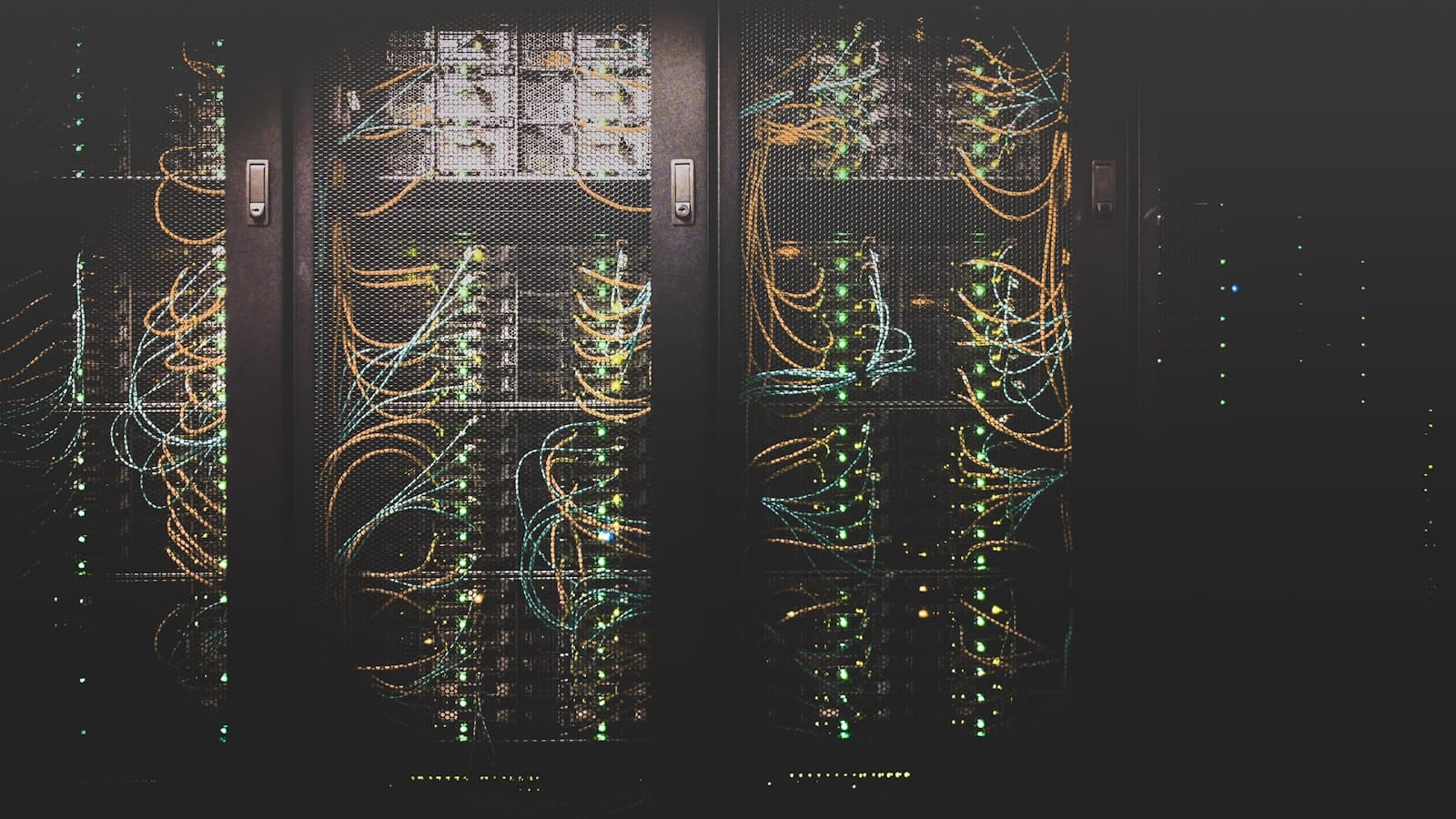 Server racks in a dark data center, threaded with glowing yellow and teal network cables