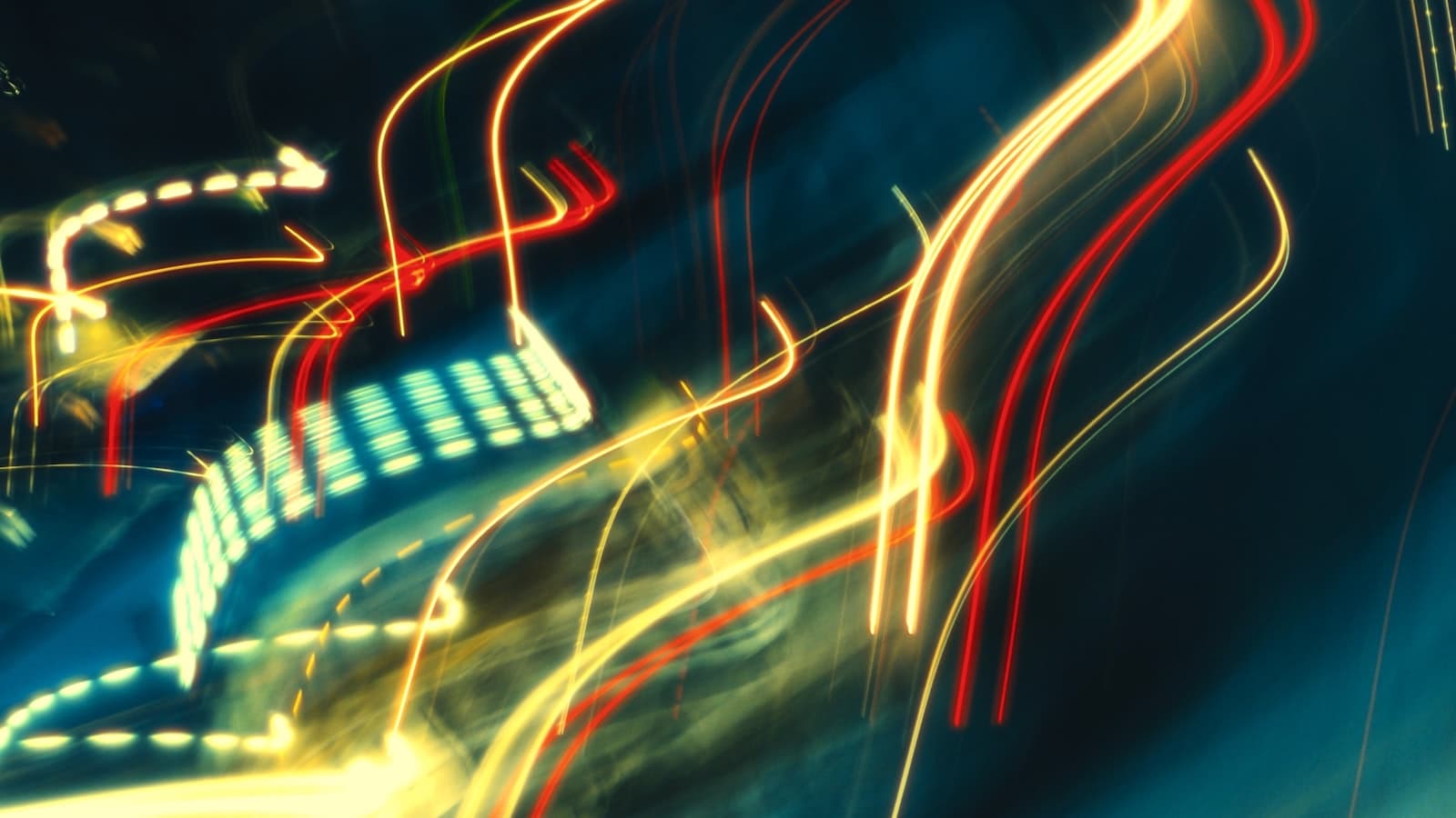 Long-exposure light trails from cars streaking through a city street at night