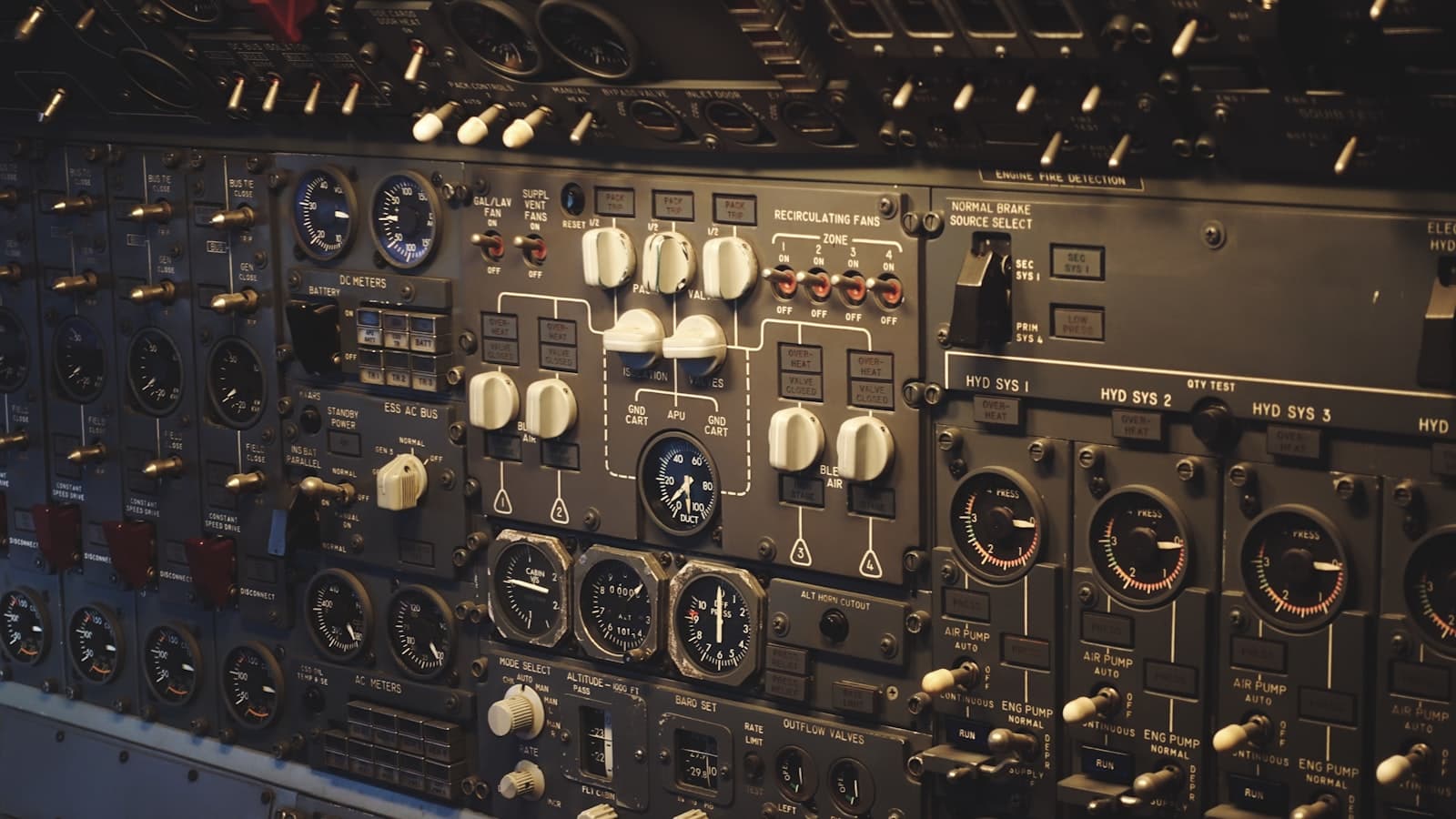 A close-up of an airplane cockpit control panel with rows of analog instruments, switches, and dials