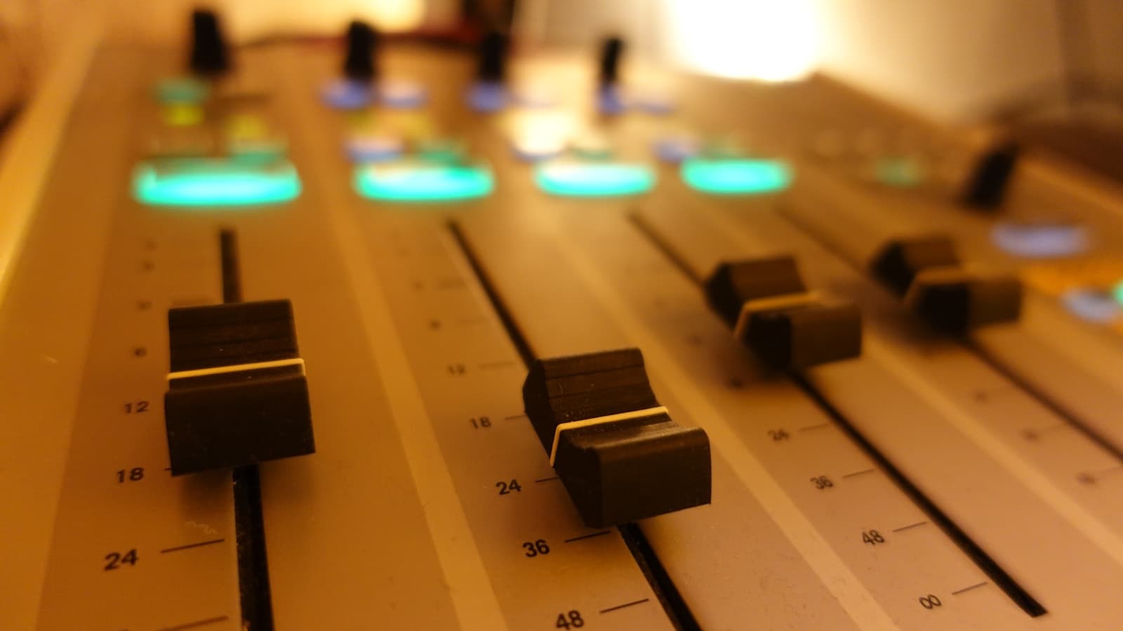 A close-up of a sound mixing console with rows of knobs, buttons, and faders